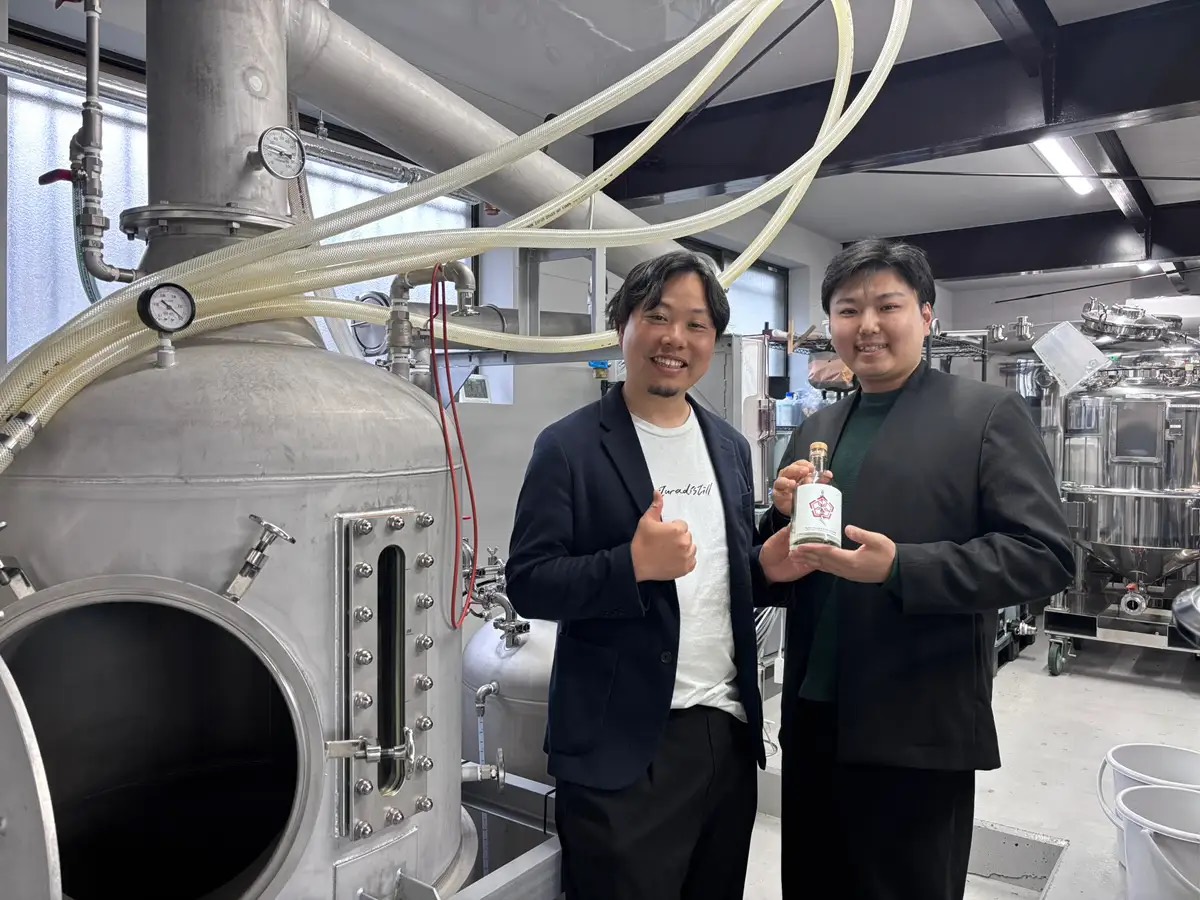 蒸留所内でボトルを手にする人物と蒸留設備